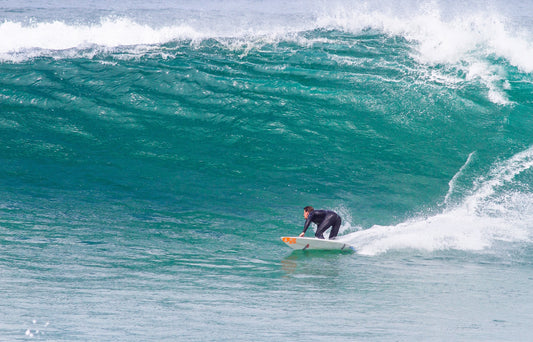 Surfer making a bottom turn on a large turquoise wave