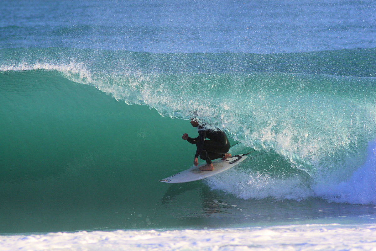 Surfer riding inside a turquoise barrel wave